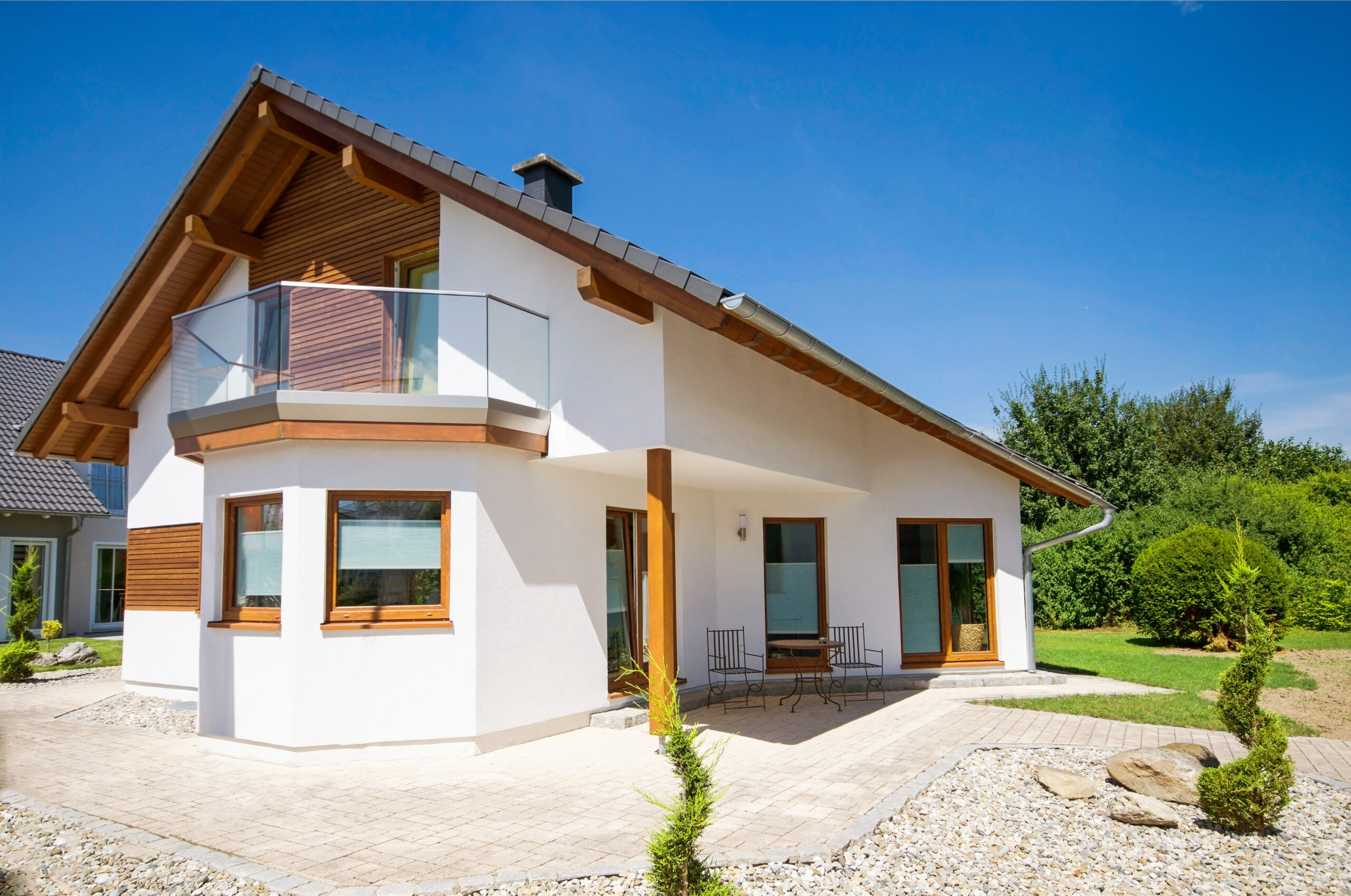 Einfamilienhaus mit Balkon, Steinvorgarten, blauer Himmel, wolkenlos