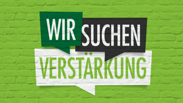 Wir suchen Verstärkung vor grüner Steinmauer